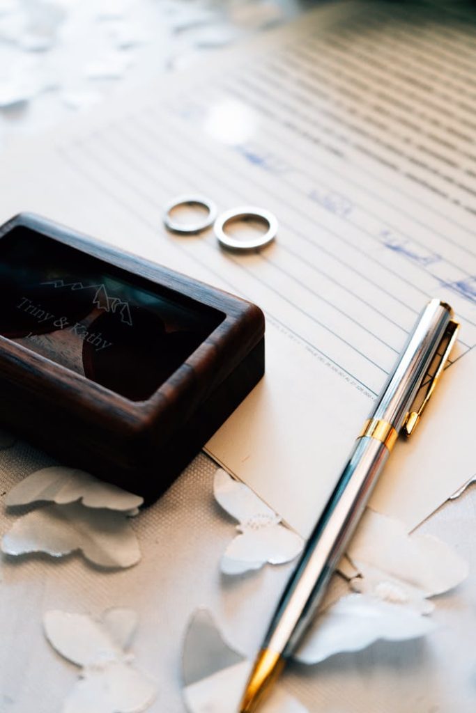 Close-up of wedding rings and pen on a marriage certificate, symbolizing union.